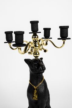 a black cat figurine sitting on top of a candelabra