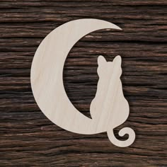 a cat sitting on top of a wooden surface next to the letter c in the shape of a crescent