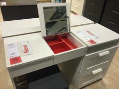 a white desk with drawers and a mirror on it's side, in a store