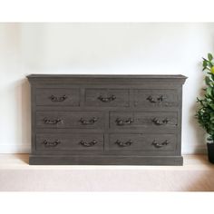 a large gray dresser sitting next to a potted plant