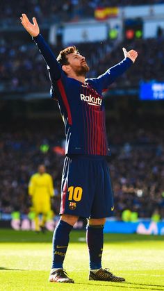 a man standing on top of a soccer field holding his arms up in the air