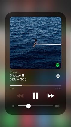 an iphone screen with the music player on it's left side, and someone swimming in the ocean