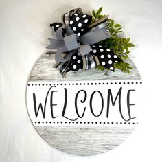 a welcome sign hanging on the side of a white wall with black and white polka dots