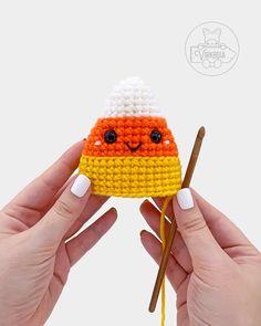 someone is holding up a small crocheted candy with chopsticks in their hands