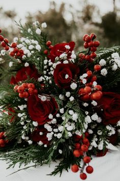 a bouquet of red roses and baby's breath is sitting on a tablecloth