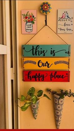 this is our happy place sign hanging on the wall with potted plants and flowers