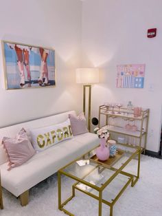 a living room with a white couch and pink decorations on the wall, coffee table and side tables