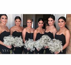 the bridesmaids are dressed in black dresses and holding bouquets of baby's breath