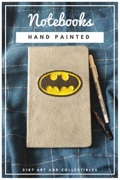 a notebook with a batman symbol painted on it and the words notebooks hand painted