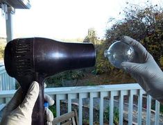 a person in white gloves holding a blow dryer up to the side of a house