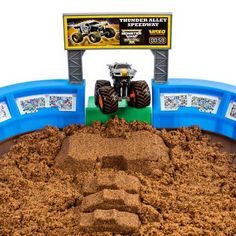 there is a toy truck in the middle of a dirt pit with monster trucks on it