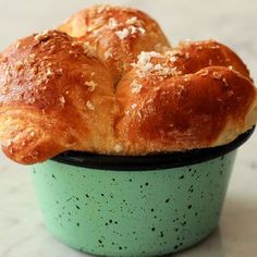 two loaves of bread sitting in a green bowl