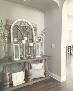 a table with candles and flowers on it in a room that has wood floors, gray walls and white trim