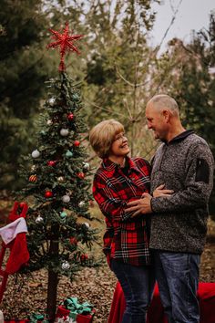 a man and woman standing next to a christmas tree