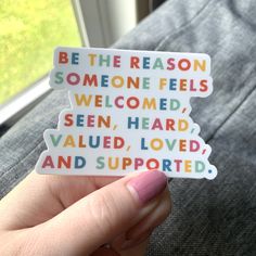 someone holding up a sticker that says be the reason someone feels welcome, seen, heard, value, loved and supported