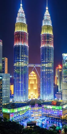 the city skyline is lit up at night with colorful lights and skyscrapers in the background