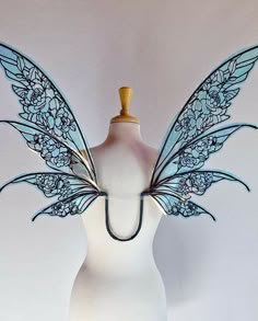 a white mannequin with blue wings and flowers on it's head is shown