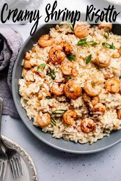 a bowl filled with shrimp and rice on top of a white table next to silverware