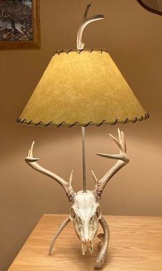 a lamp that has a deer skull on it with a yellow shade over the base