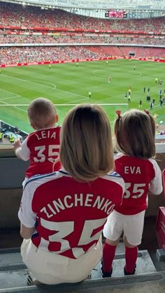 two children in red and white jerseys sitting on the bleachers at a soccer game