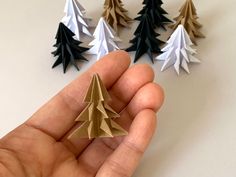 a hand is holding some origami trees