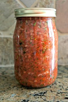 a jar filled with red sauce sitting on top of a counter