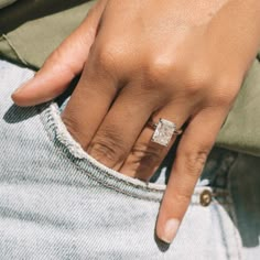 a close up of a person's hand with a ring on their finger, wearing jeans