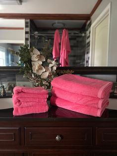 two pink towels stacked on top of a wooden dresser