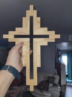 a person is holding a wooden cross in their hand and it looks like they are making something out of wood