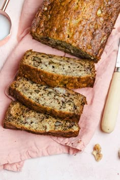 sliced loaf of banana bread sitting on top of a pink napkin next to a knife