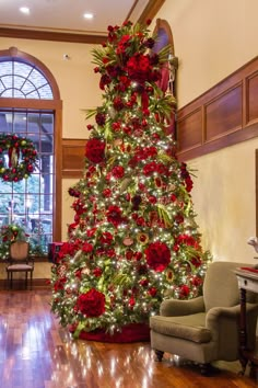 a decorated christmas tree in the middle of a living room with red and green decorations