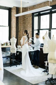 a man and woman standing in front of mannequins wearing wedding gowns