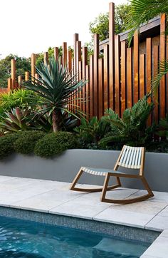 a wooden rocking chair sitting next to a swimming pool