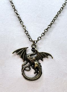 This necklace features a Mythical Dragon that measures 1 3/4"  by 1 3/4". The dragon hangs from 23" of Brass Rolo Chain. Dragon Pendant Necklaces, Brass Dragon, Chain Making, Dragon Necklace, Magical Jewelry, Brass Antique, Dragon Pendant, Rolo Chain, The Dragon