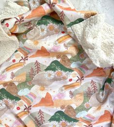 an unmade blanket with flowers and trees on it