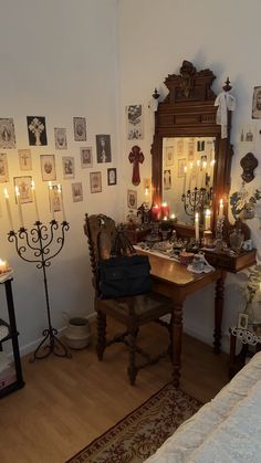 a room with candles and pictures on the wall, along with a desk in front of a mirror