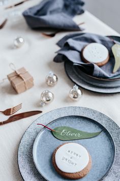 a plate with a cookie on it sitting next to other plates and silverware,