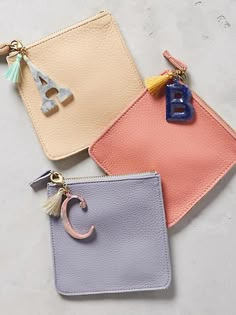 three small purses with keychains hanging from the handles and two different colors