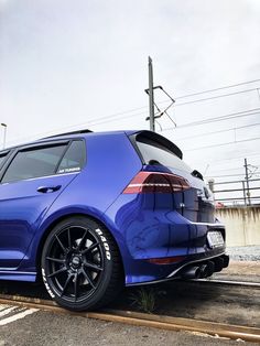 the rear end of a blue car parked in a parking lot next to power lines