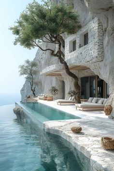 an outdoor swimming pool with chaise lounges and trees on the cliff above it