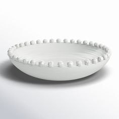 a white bowl with beads on the rim