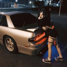 two people standing next to a parked car at night