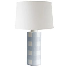 a blue and white table lamp with a white shade on the top, in front of a white background