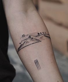 a man's arm with mountains and arrows tattoo on the left side of his arm