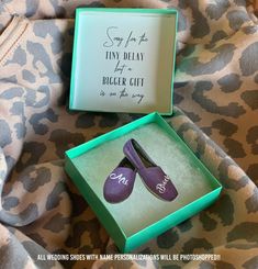 two pairs of purple shoes in a green box on top of a leopard print blanket