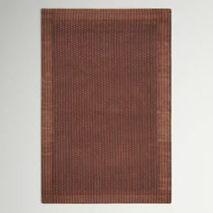 an orange and brown area rug hanging on a wall