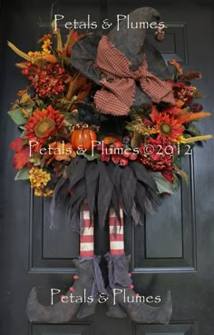 an autumn wreath on the front door with pumpkins and leaves hanging from it's sides