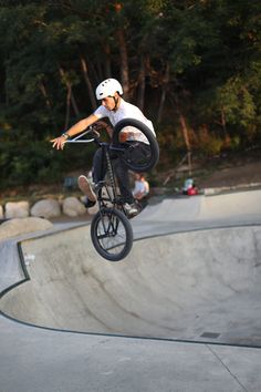 a man riding a bike up the side of a skateboard ramp at a skate park