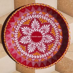 a red and yellow plate sitting on top of a tile floor next to a wall