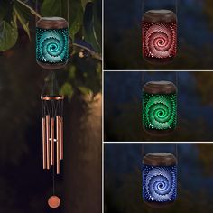 four different colored lights hanging from a tree branch in the dark, one with a wind chime on it